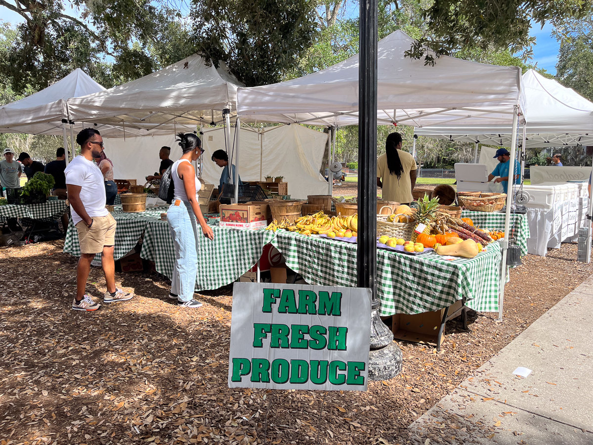 white tents with fresh produce sign and stands